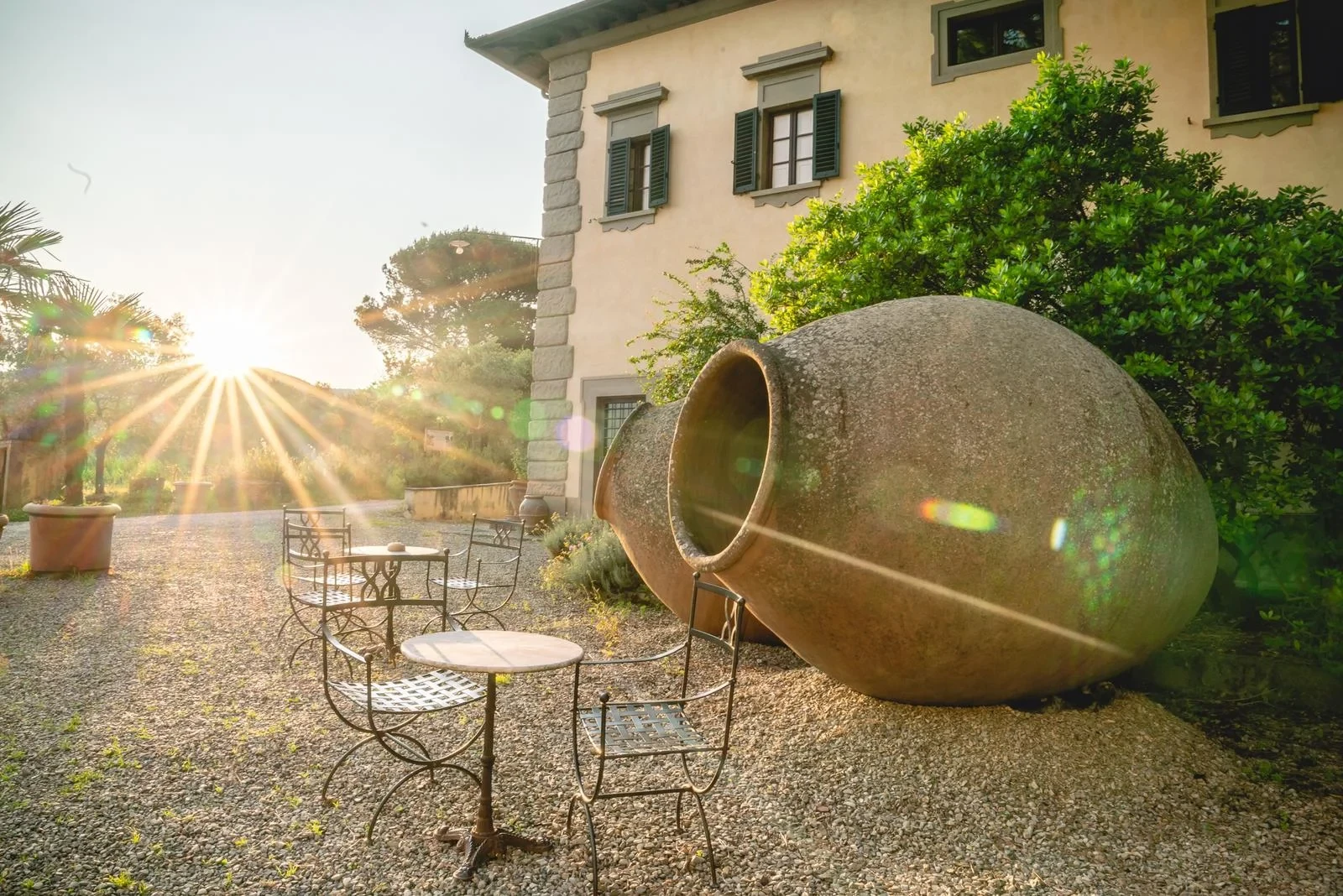 Tavolini e sole al tramonto in giardino italiano.
