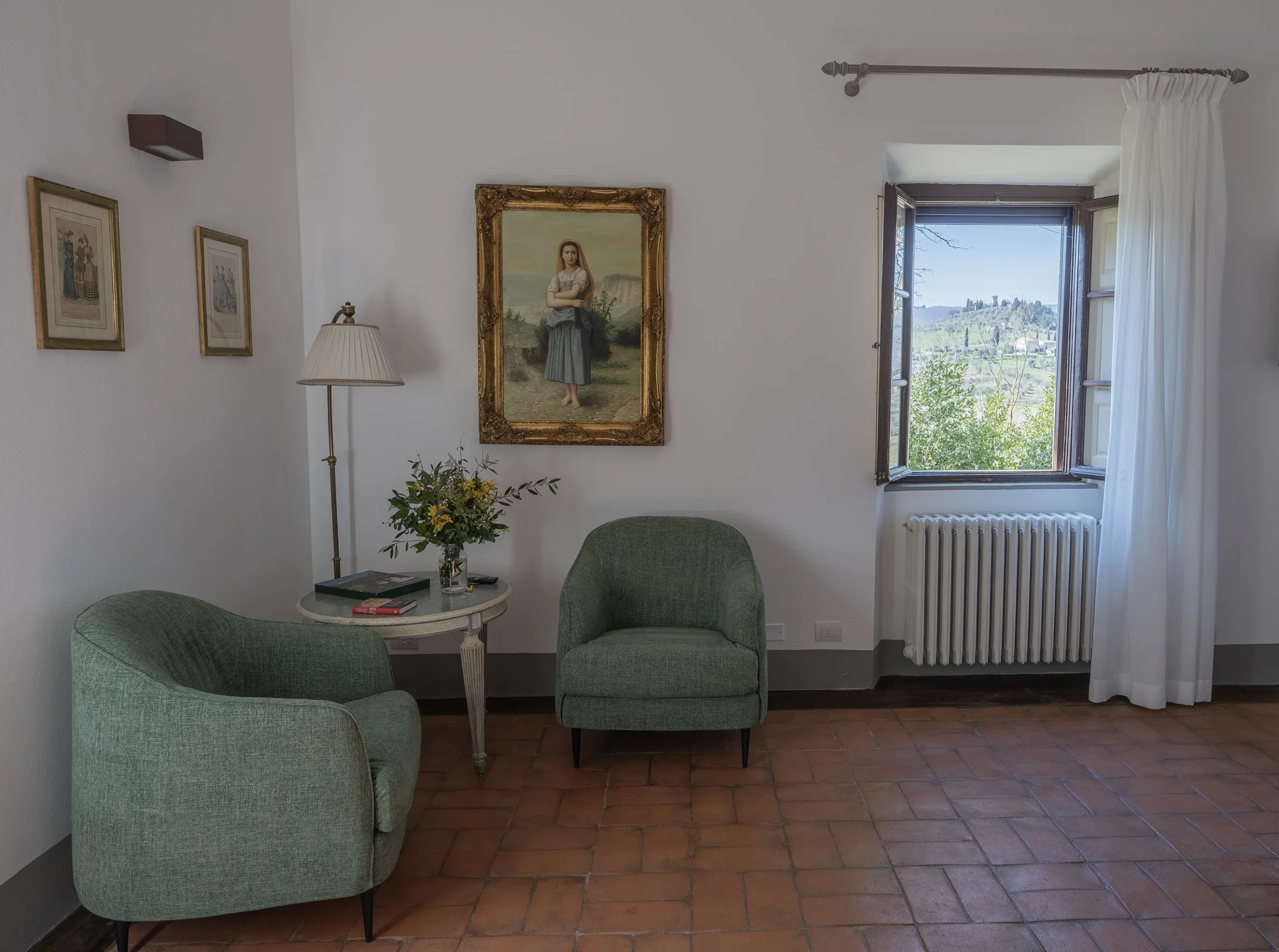 Salotto con poltrone verdi e finestra aperta.