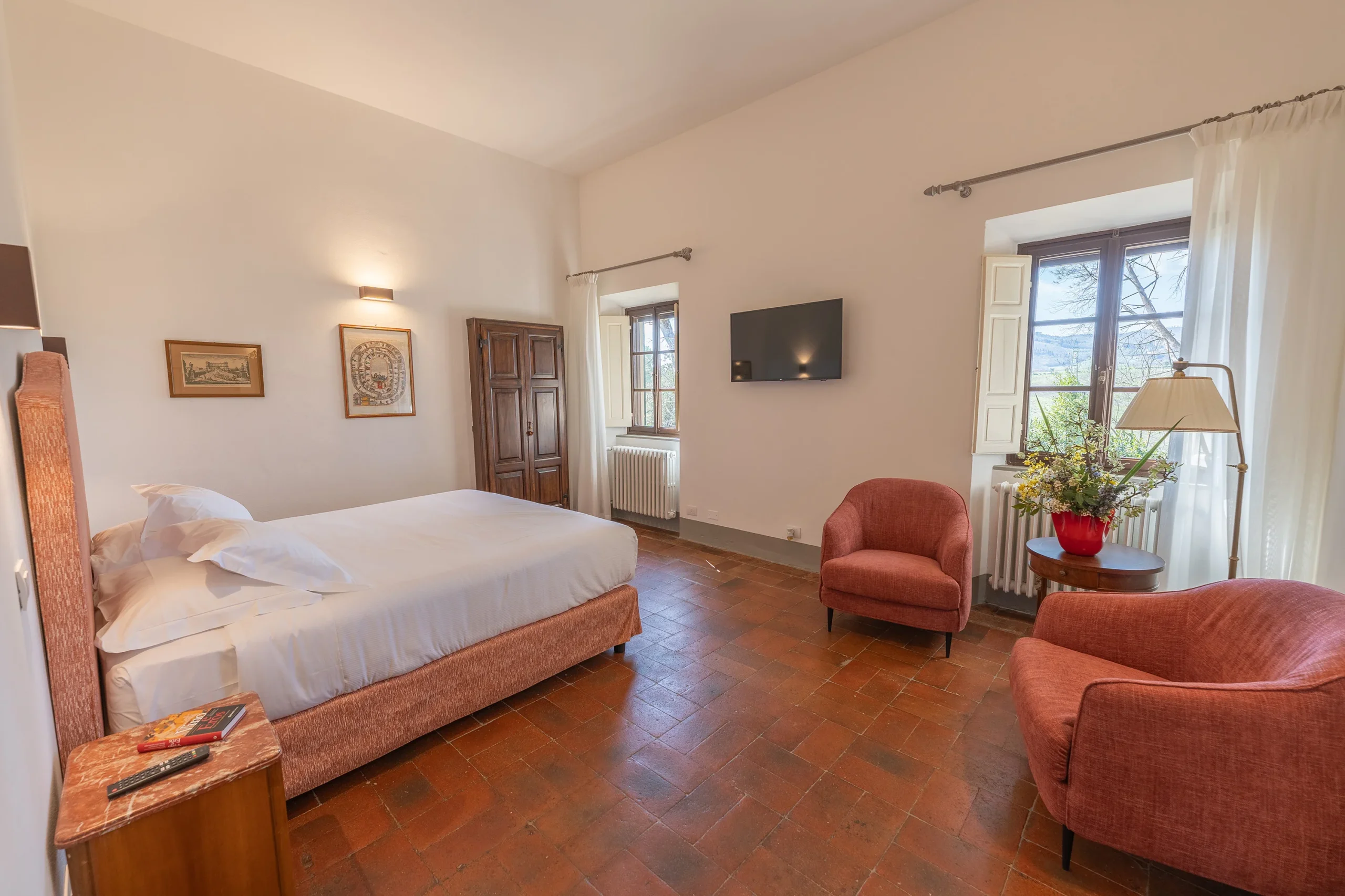 Camera da letto accogliente con finestra e poltrone rosse.