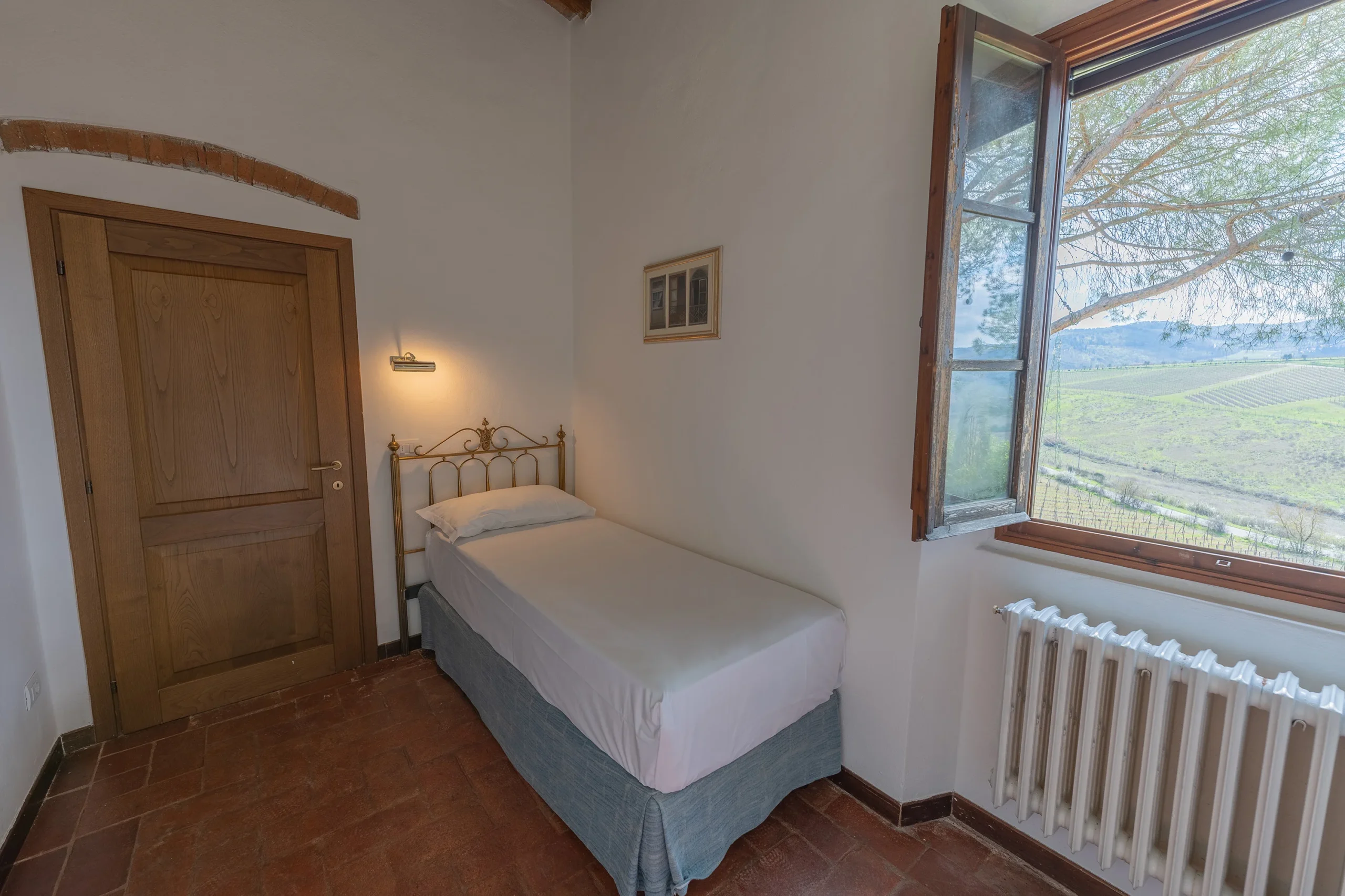 Stanza con letto singolo e finestra aperta.