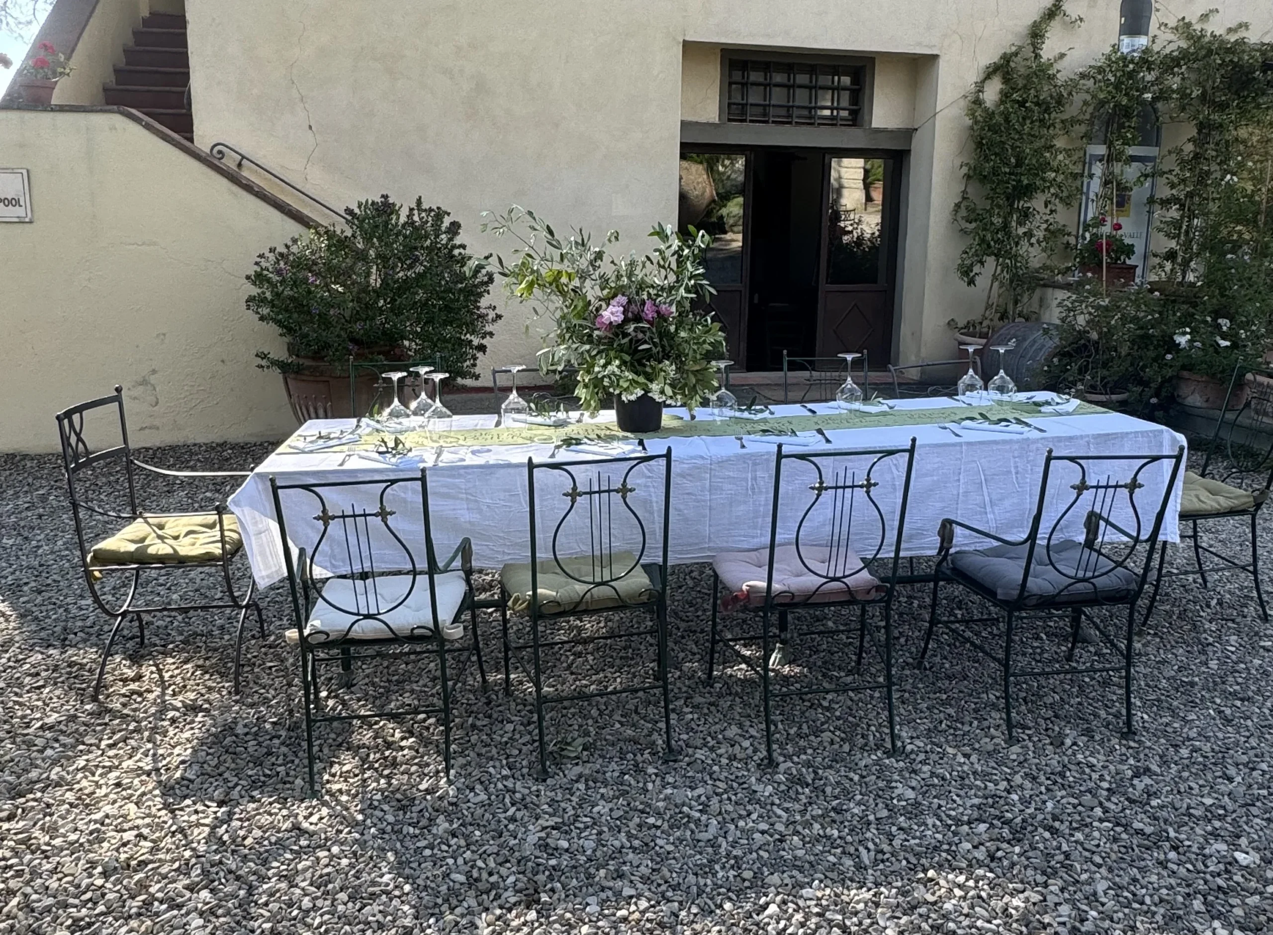 Tavolo all'aperto apparecchiato con fiori e sedie.