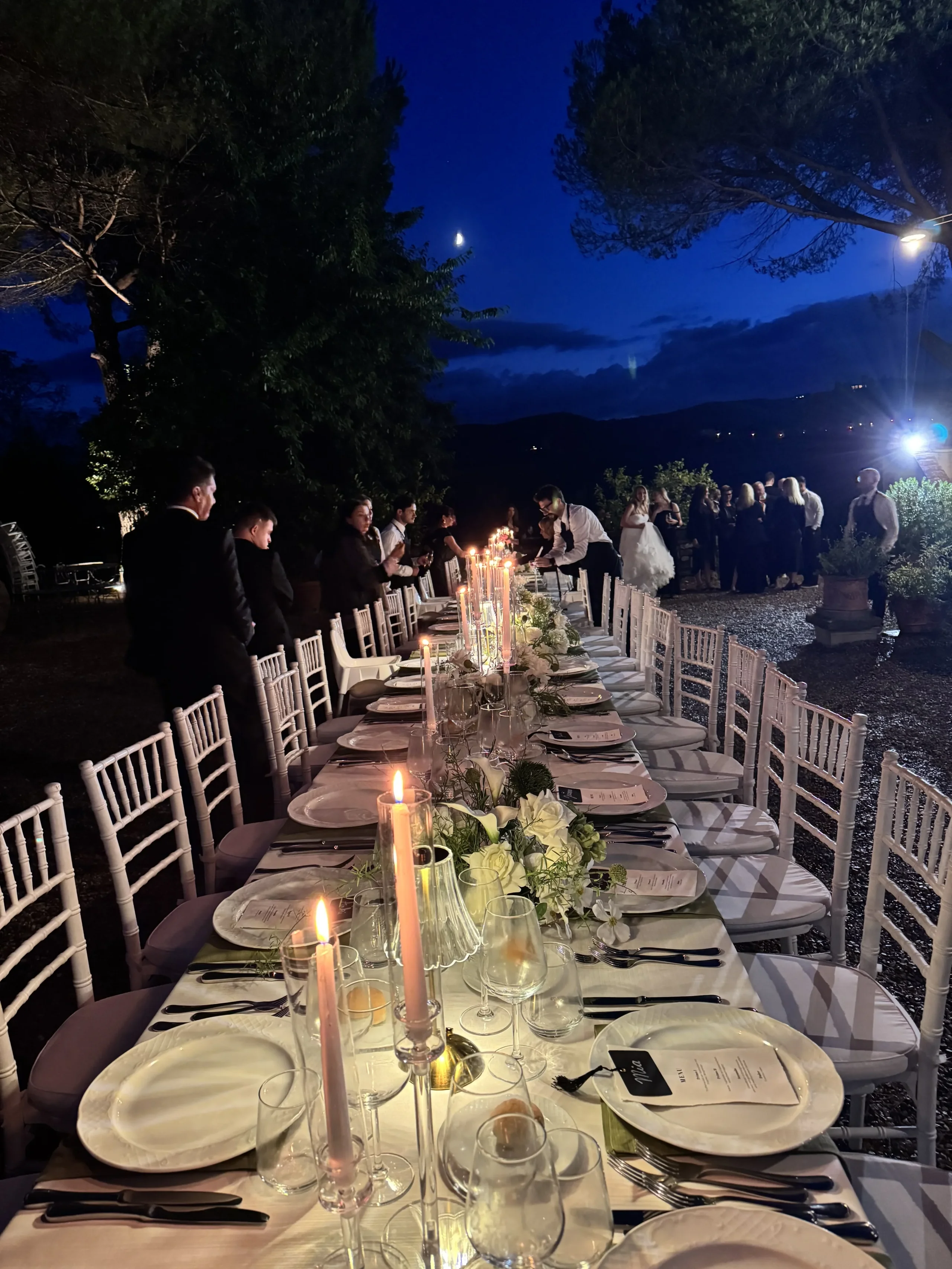 Cena all'aperto con tavolo decorato e commensali.