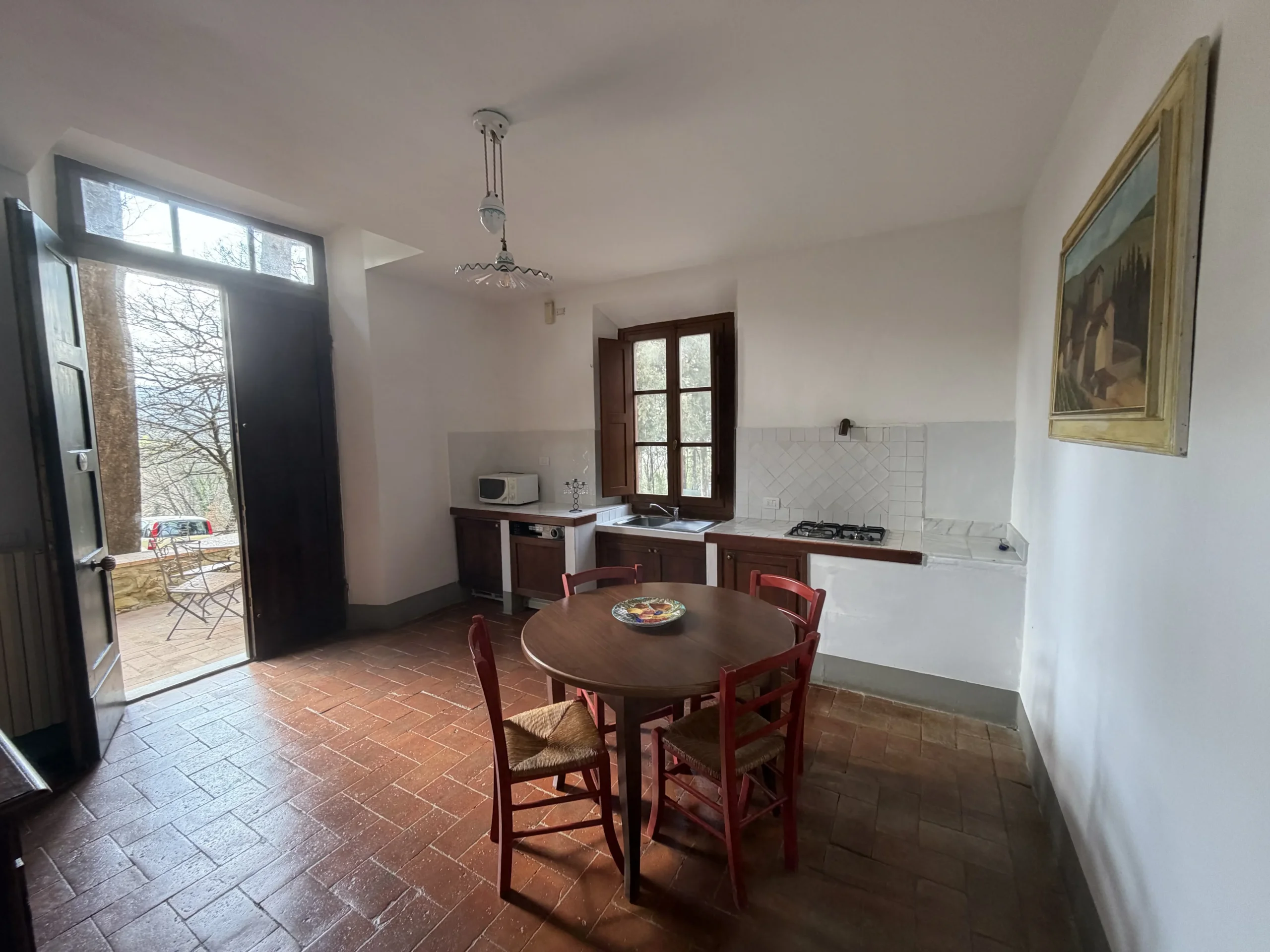 Cucina rustica con tavolo e sedie rosse.