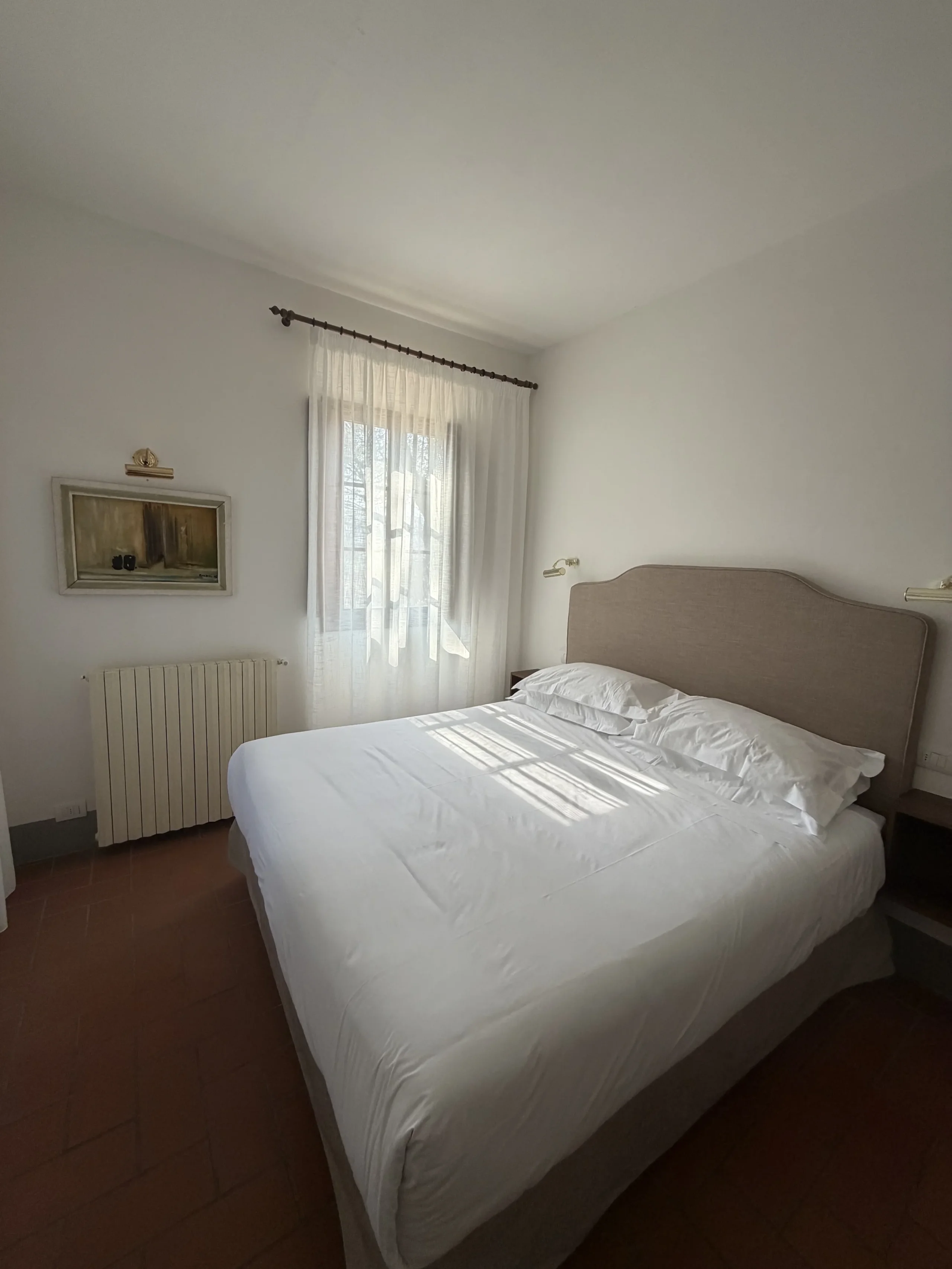 Camera da letto con finestra luminosa e letto matrimoniale.