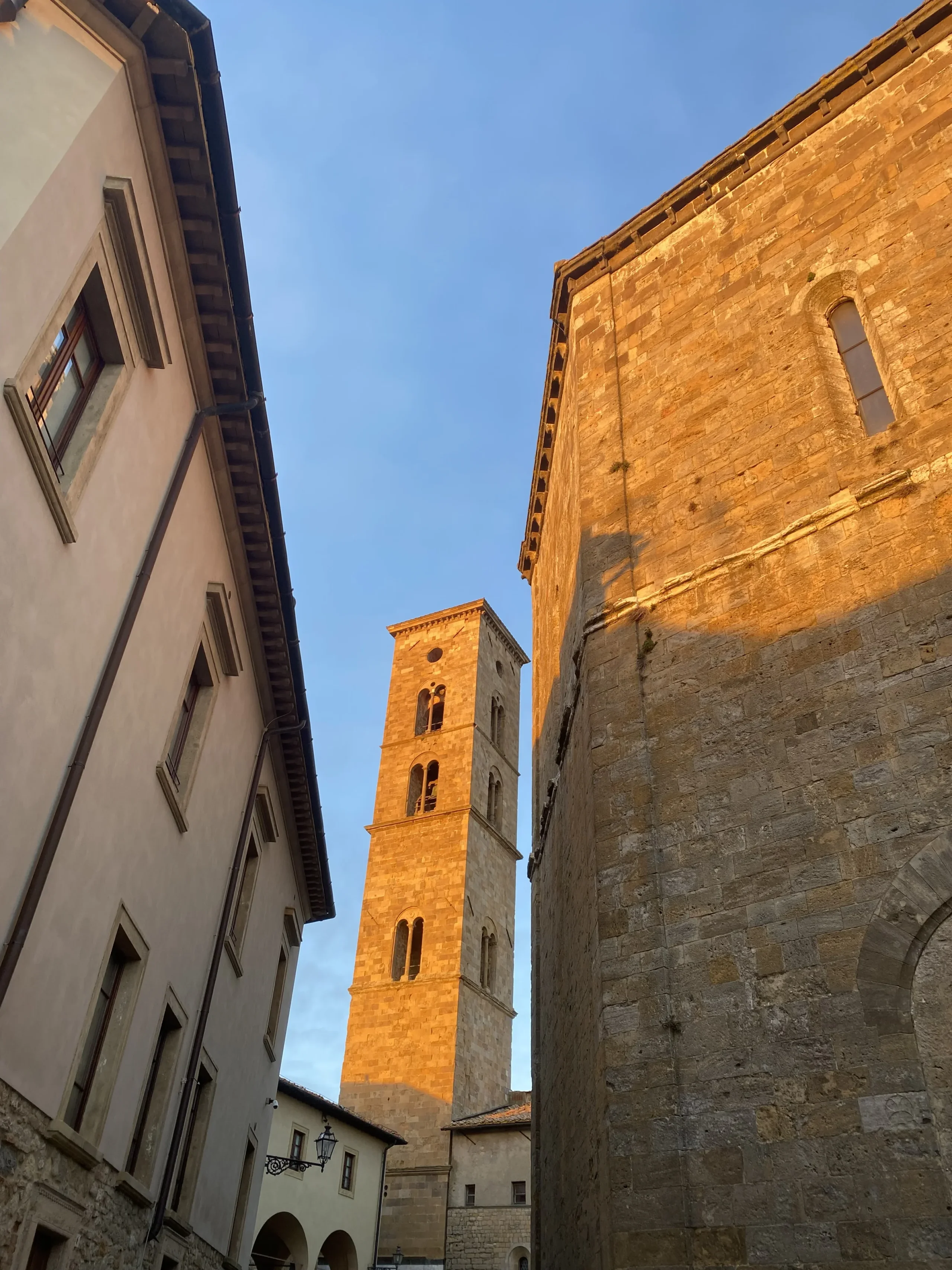 Torre di pietra al tramonto tra edifici storici.