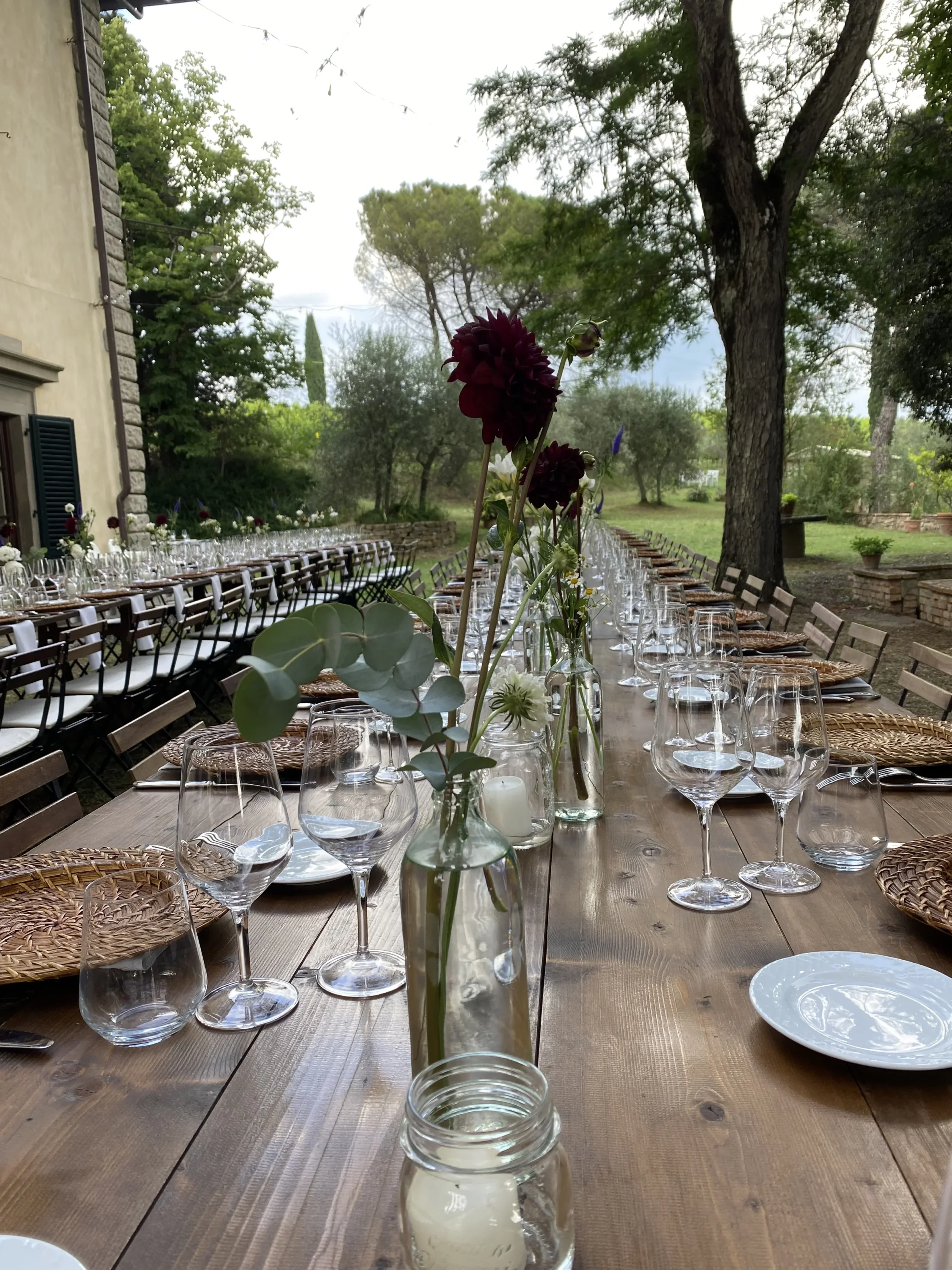 Tavola all'aperto con bicchieri e fiori.